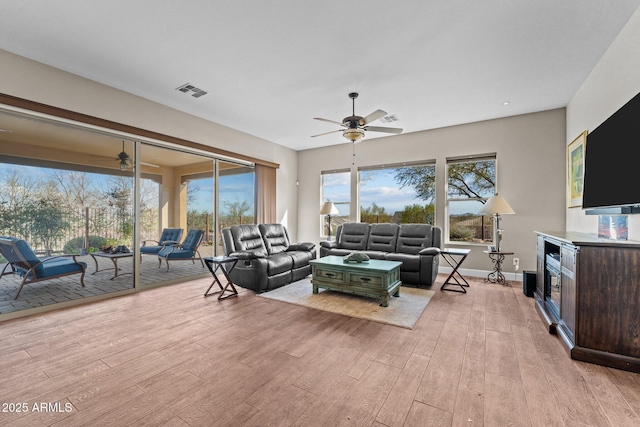 living area with visible vents, plenty of natural light, a ceiling fan, and light wood finished floors