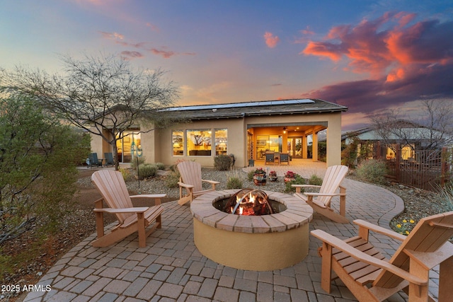 patio terrace at dusk featuring fence and an outdoor fire pit