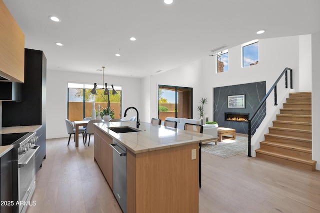 kitchen featuring appliances with stainless steel finishes, modern cabinets, a premium fireplace, and a sink