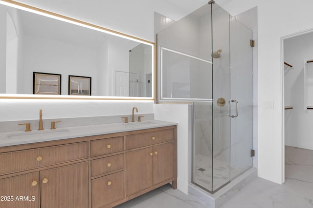 full bath featuring a stall shower, marble finish floor, double vanity, and a sink