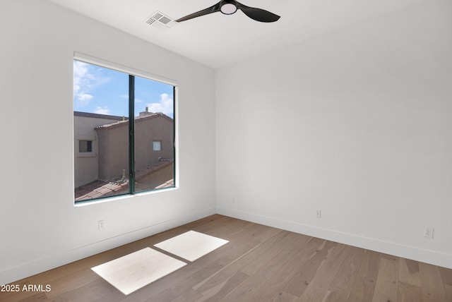 spare room featuring visible vents, wood finished floors, baseboards, and ceiling fan