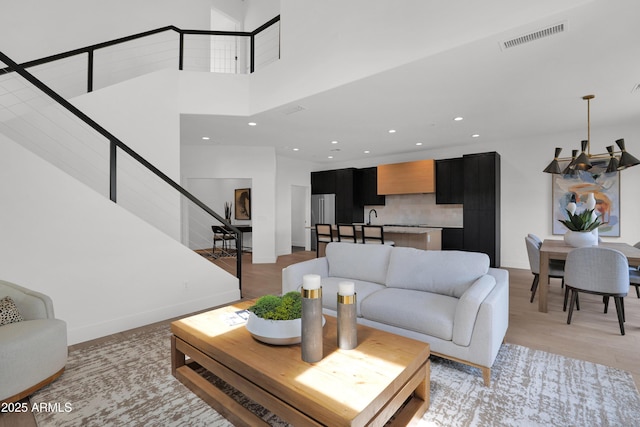 living area featuring recessed lighting, baseboards, visible vents, stairs, and a high ceiling