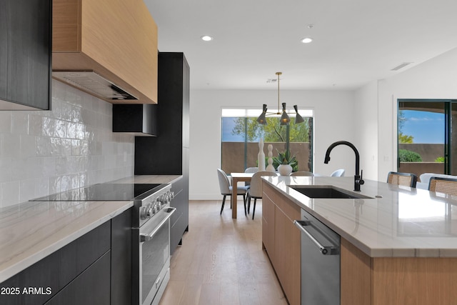 kitchen with modern cabinets, visible vents, a sink, premium range hood, and stainless steel appliances