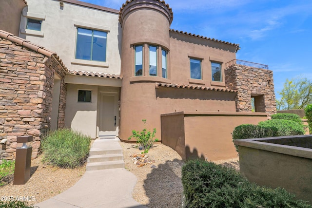 view of front of home with a tile roof, stucco siding, and stone siding