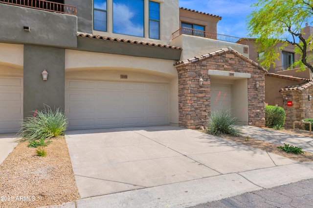 mediterranean / spanish-style house featuring an attached garage, stucco siding, a tile roof, a balcony, and driveway