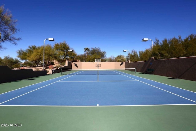 view of tennis court featuring community basketball court and fence