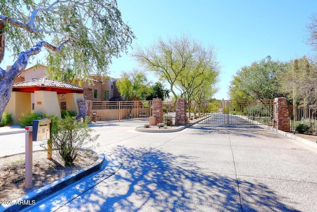 view of street with curbs, a gated entry, and a gate