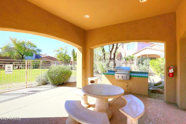view of patio with area for grilling, fence, and a grill