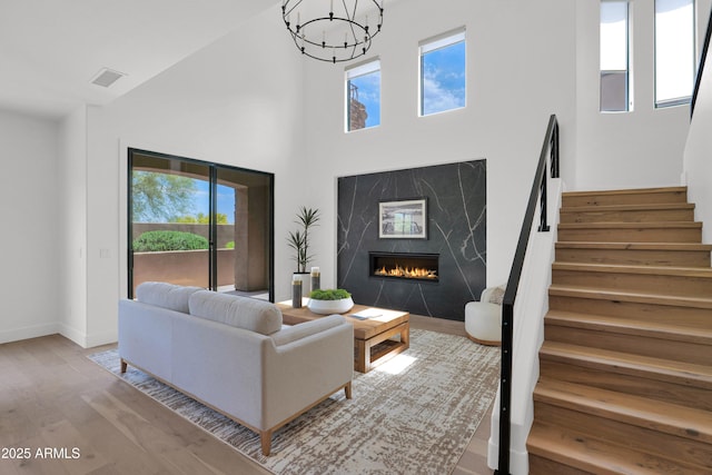 living area featuring wood finished floors, a towering ceiling, a healthy amount of sunlight, and stairs