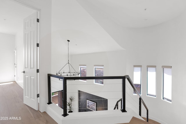 staircase featuring baseboards, a notable chandelier, and wood finished floors