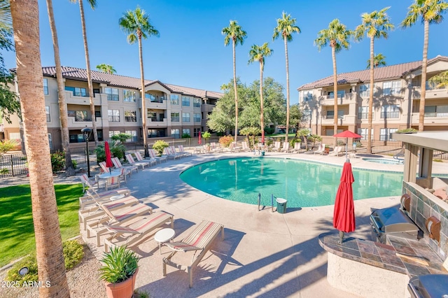 community pool with a patio area and fence