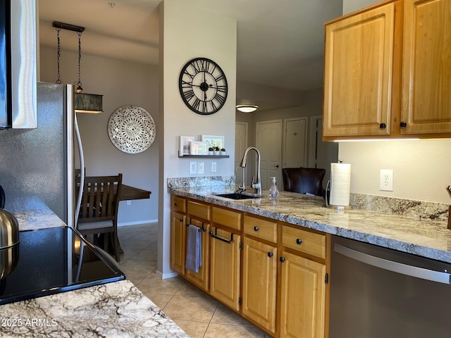 kitchen with appliances with stainless steel finishes, a sink, light tile patterned floors, light stone countertops, and baseboards