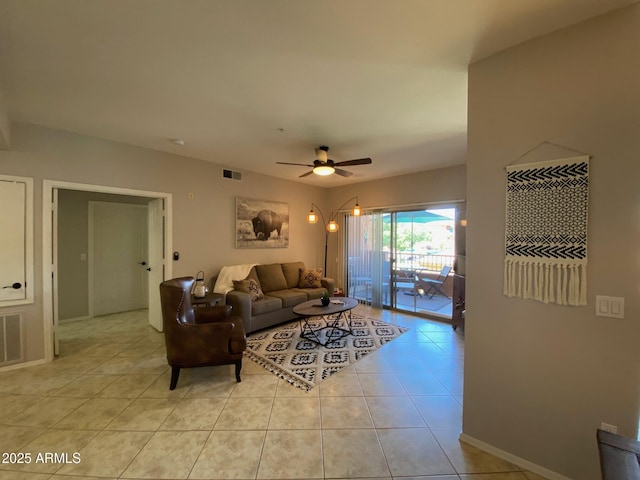 living area featuring light tile patterned flooring, a ceiling fan, and baseboards