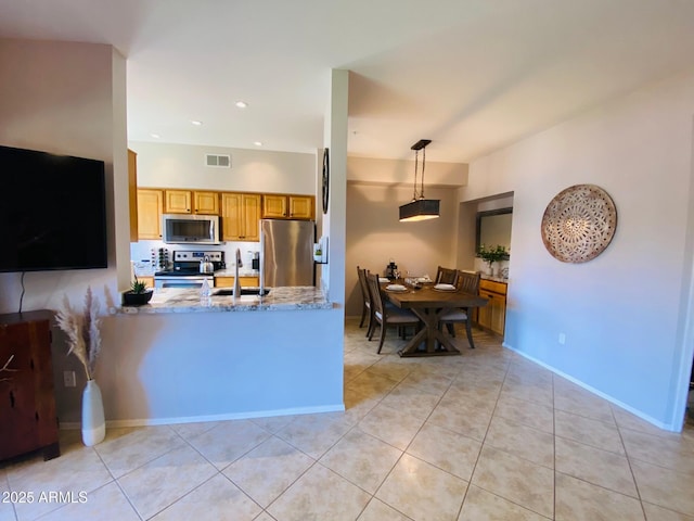 kitchen featuring stainless steel appliances, light tile patterned floors, hanging light fixtures, a peninsula, and a sink