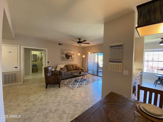 living area with ceiling fan, healthy amount of natural light, baseboards, and light tile patterned floors