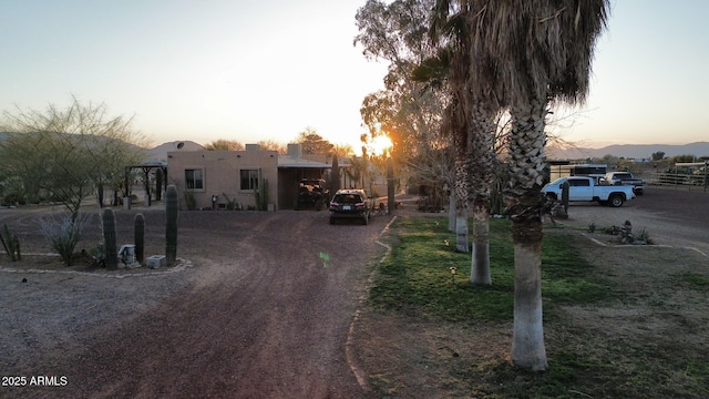 view of front of house featuring stucco siding and dirt driveway