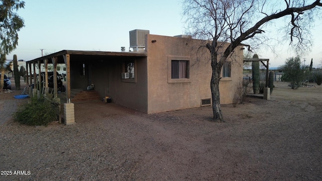 exterior space with stucco siding, visible vents, and cooling unit