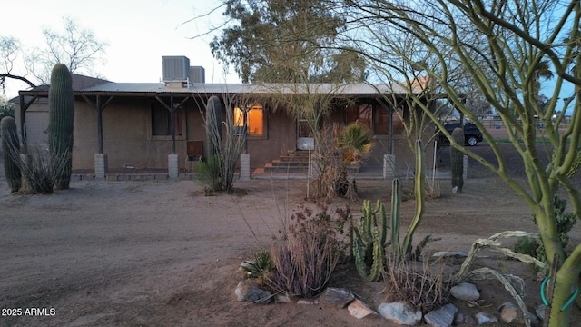 view of front facade with cooling unit, a porch, and stucco siding