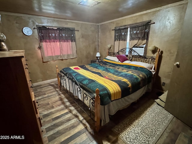 bedroom with visible vents, ornamental molding, baseboards, and wood finished floors