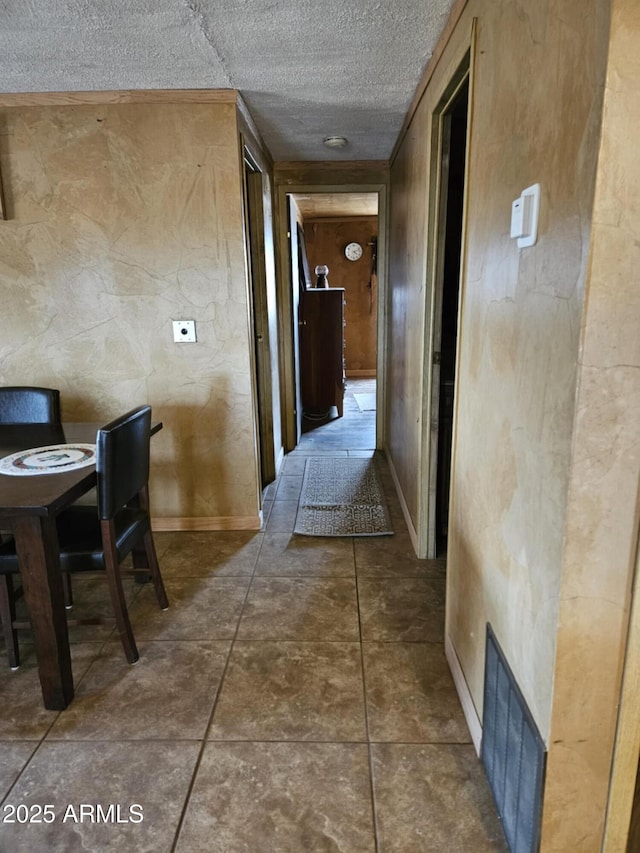 corridor featuring visible vents, a textured ceiling, and baseboards