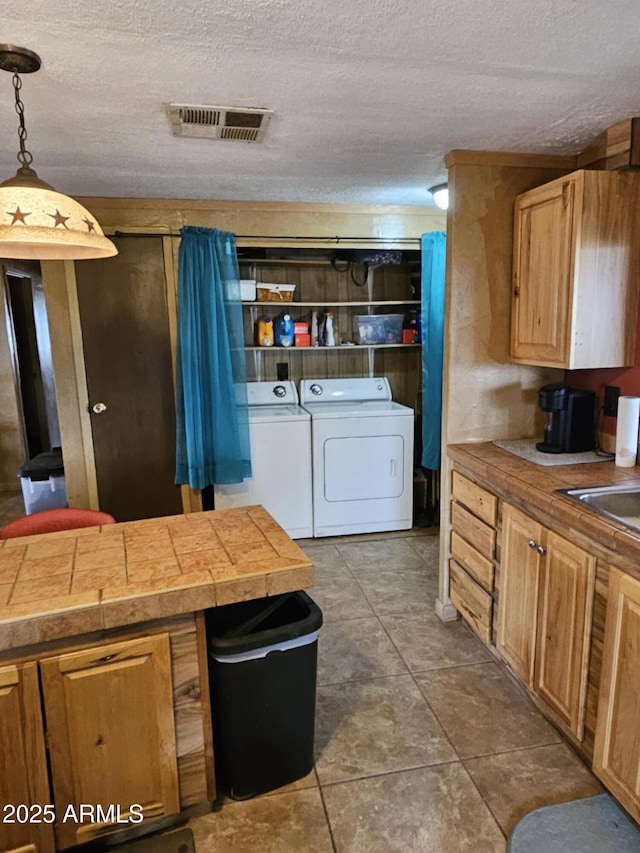 kitchen with decorative light fixtures, visible vents, a textured ceiling, and separate washer and dryer