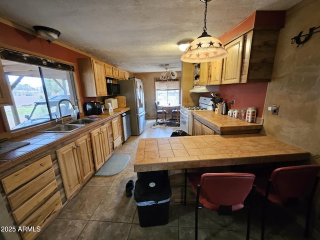 kitchen with a peninsula, gas range gas stove, a sink, tile counters, and black microwave