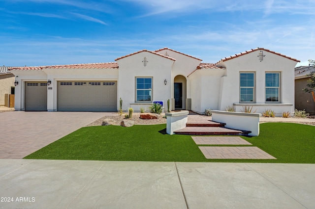 mediterranean / spanish-style home with a garage and a front lawn