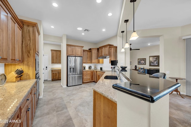 kitchen featuring stainless steel appliances, a sink, decorative light fixtures, and brown cabinets