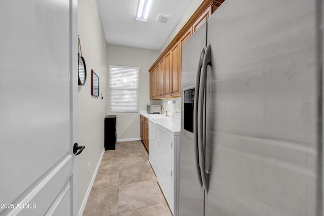 kitchen with baseboards, visible vents, stainless steel fridge with ice dispenser, washing machine and clothes dryer, and light countertops