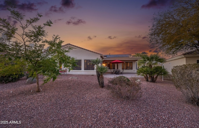 view of front of property featuring a patio, stucco siding, and roof mounted solar panels