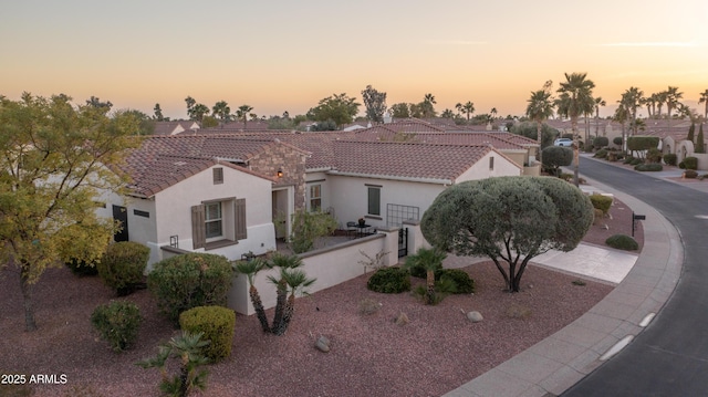 view of front of house featuring fence, a tile roof, and stucco siding