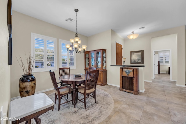 dining area featuring visible vents, a notable chandelier, and baseboards