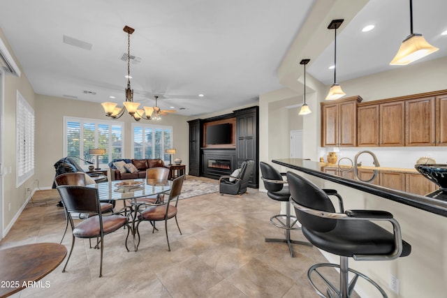 dining room featuring recessed lighting, visible vents, a glass covered fireplace, a chandelier, and baseboards