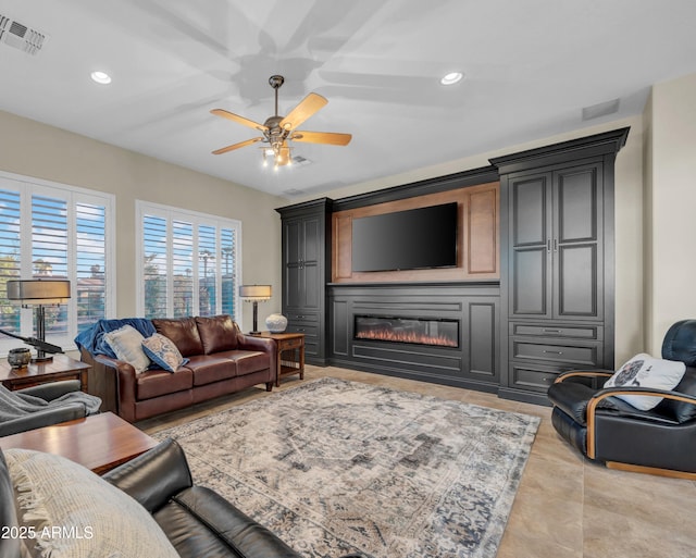 living area with light tile patterned floors, recessed lighting, visible vents, a glass covered fireplace, and ceiling fan