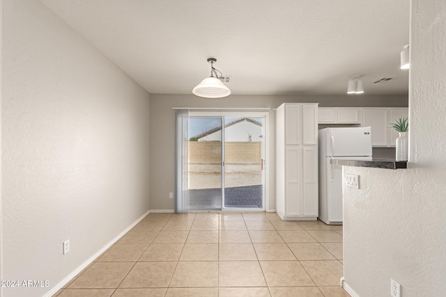 kitchen featuring white cabinets, white fridge, hanging light fixtures, and light tile patterned floors