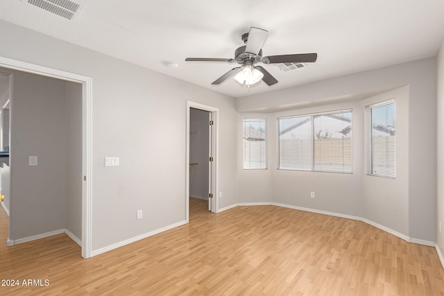 unfurnished bedroom with a walk in closet and light hardwood / wood-style floors