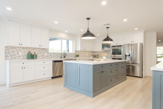 kitchen with white cabinets, light hardwood / wood-style flooring, stainless steel appliances, pendant lighting, and a kitchen island