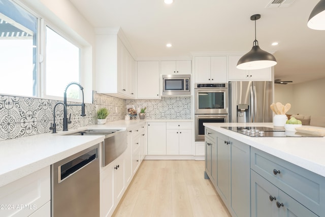 kitchen with light hardwood / wood-style flooring, decorative light fixtures, appliances with stainless steel finishes, and white cabinets