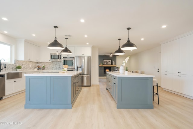 kitchen featuring a center island, stainless steel appliances, hanging light fixtures, and white cabinets