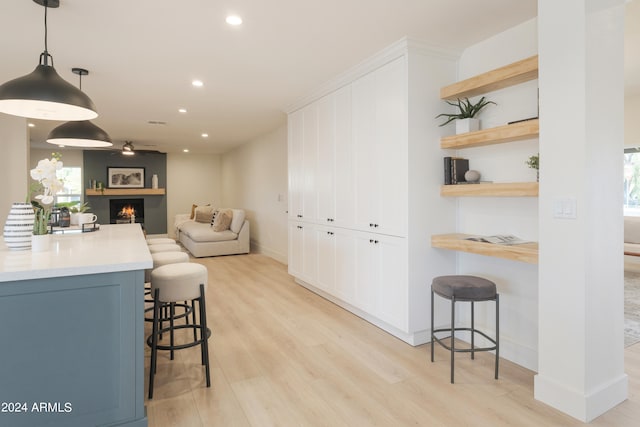 kitchen featuring light wood-type flooring, pendant lighting, blue cabinetry, and a breakfast bar