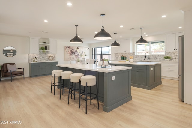 kitchen with a large island, light hardwood / wood-style floors, white cabinetry, and hanging light fixtures