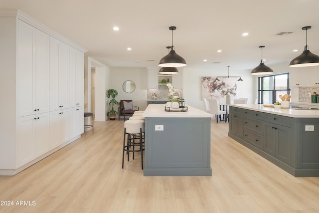 kitchen with a large island, white cabinets, decorative backsplash, and hanging light fixtures