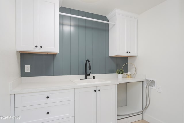 kitchen with white cabinets, light stone countertops, and sink