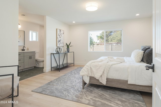 bedroom with ensuite bath and light hardwood / wood-style flooring