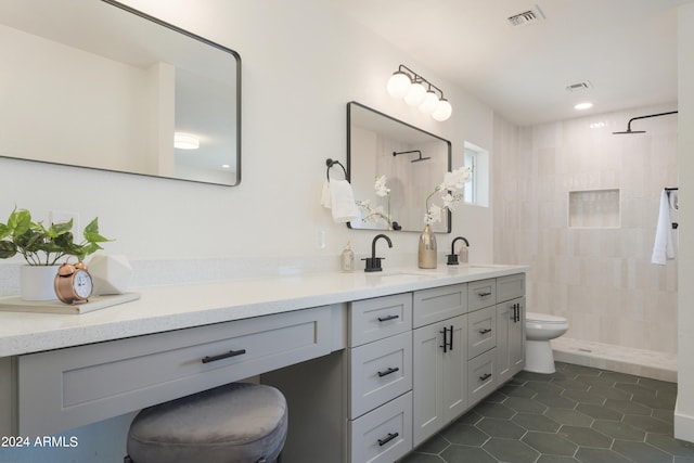 bathroom with vanity, toilet, tiled shower, and tile patterned floors