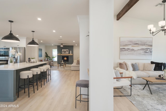 living room featuring lofted ceiling with beams, light hardwood / wood-style flooring, and an inviting chandelier