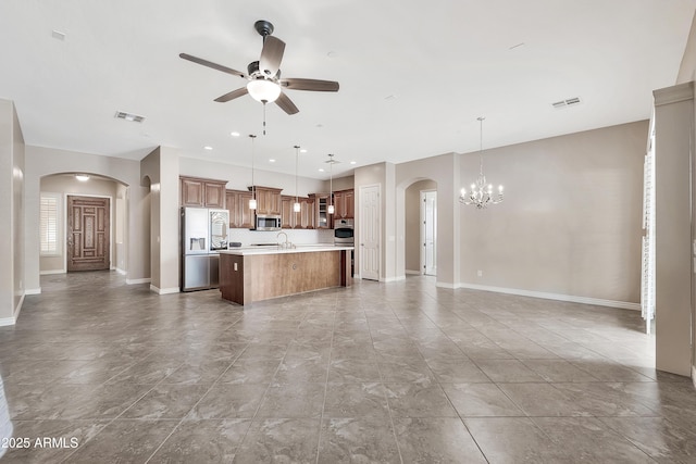 kitchen with open floor plan, light countertops, ceiling fan with notable chandelier, arched walkways, and stainless steel appliances