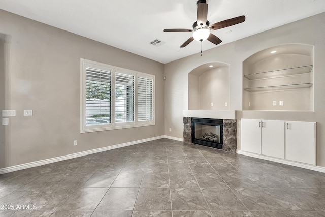 unfurnished living room featuring visible vents, built in shelves, baseboards, a fireplace, and a ceiling fan