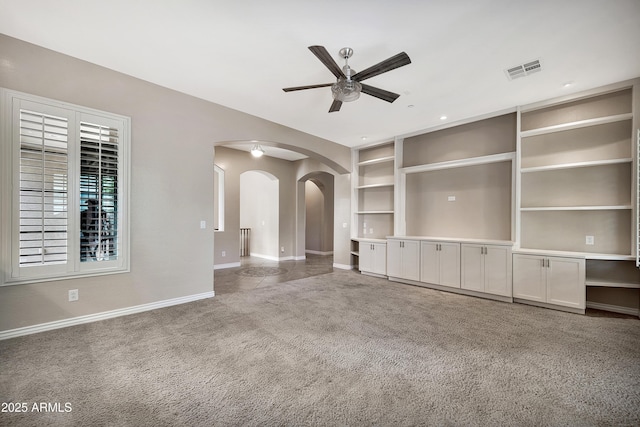 unfurnished living room featuring visible vents, a ceiling fan, arched walkways, carpet, and baseboards