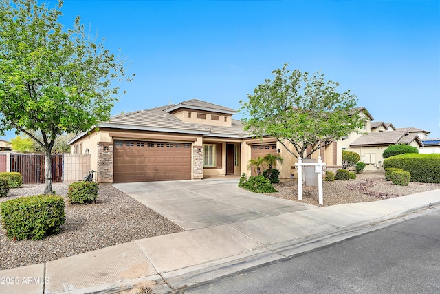 view of front of property with fence, stucco siding, a garage, stone siding, and driveway